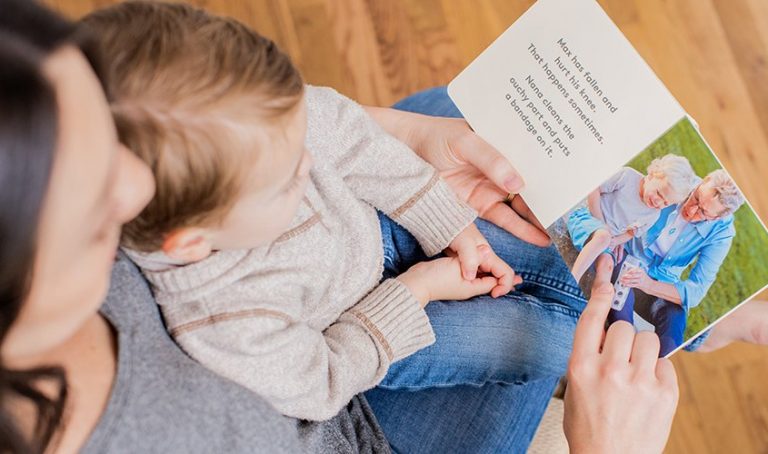 Toddler sitting on a woman's lap looking at a book together