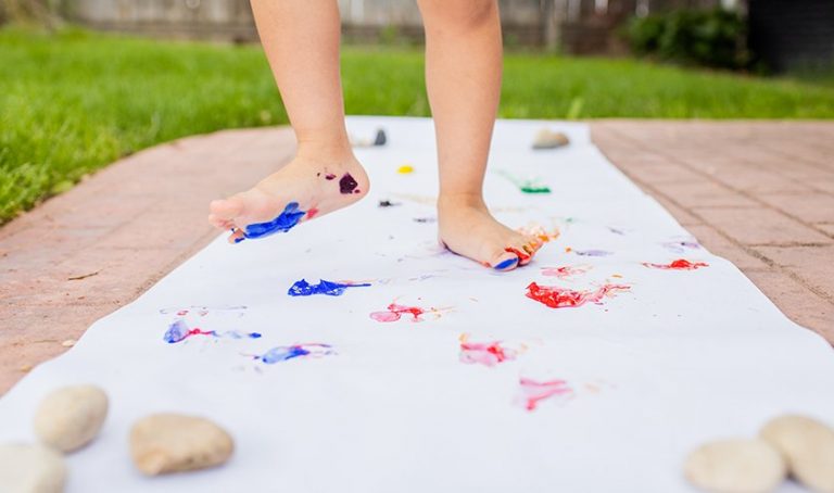 Young child with paint on their feet walking on paper