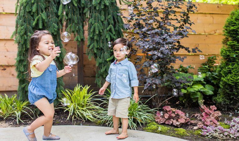 Two young children outside playing with bubbles