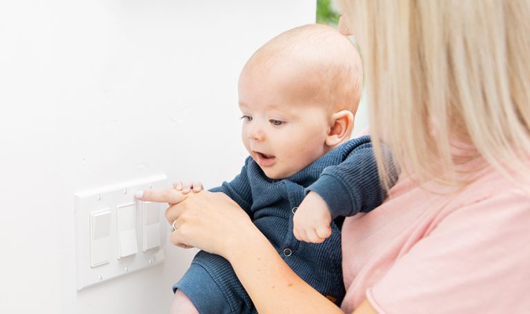 Woman holding a baby while flicking the light switch on and off